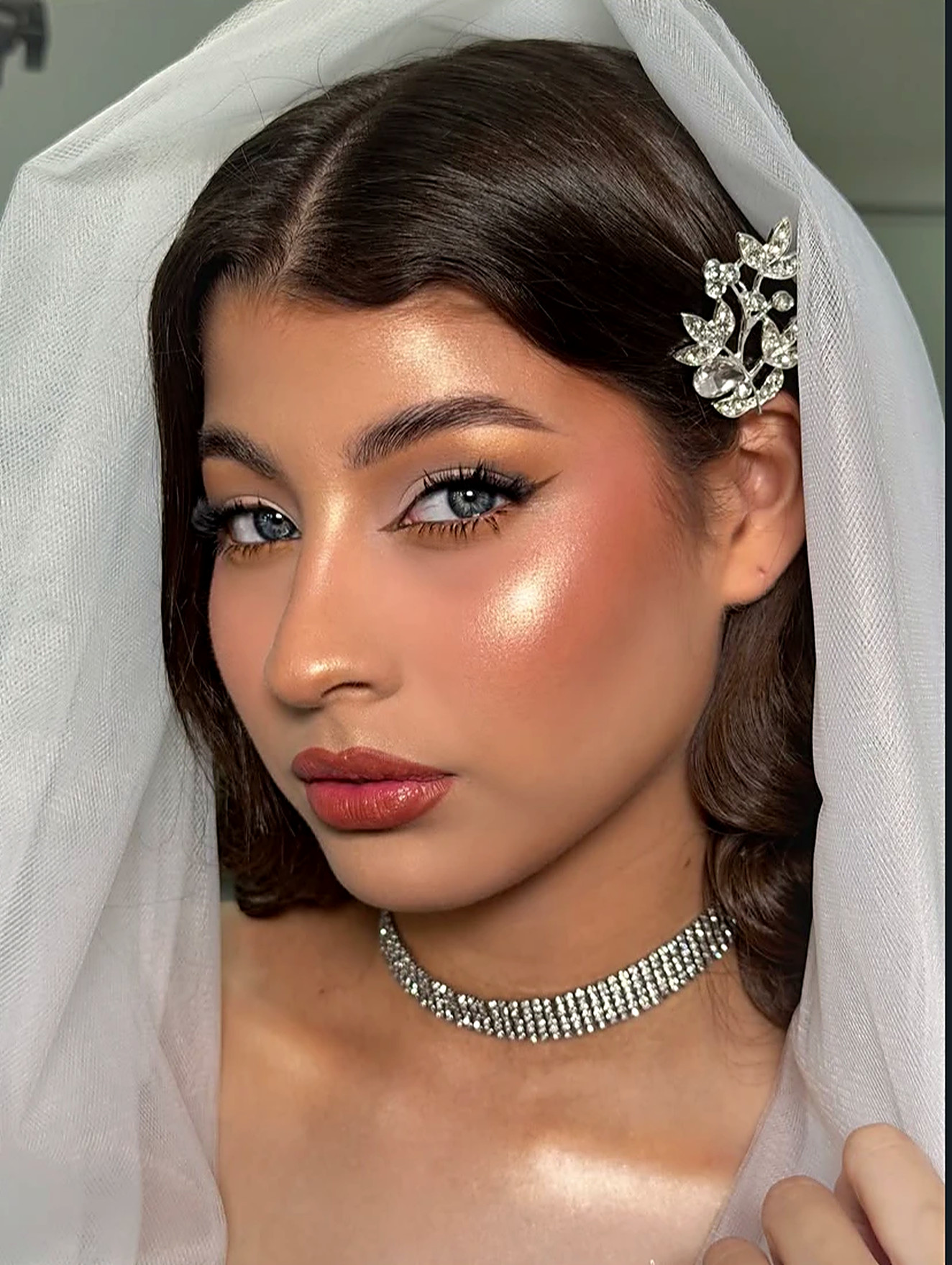 Novia con velo y maquillaje de piel blindada, iluminada y con labios rosados