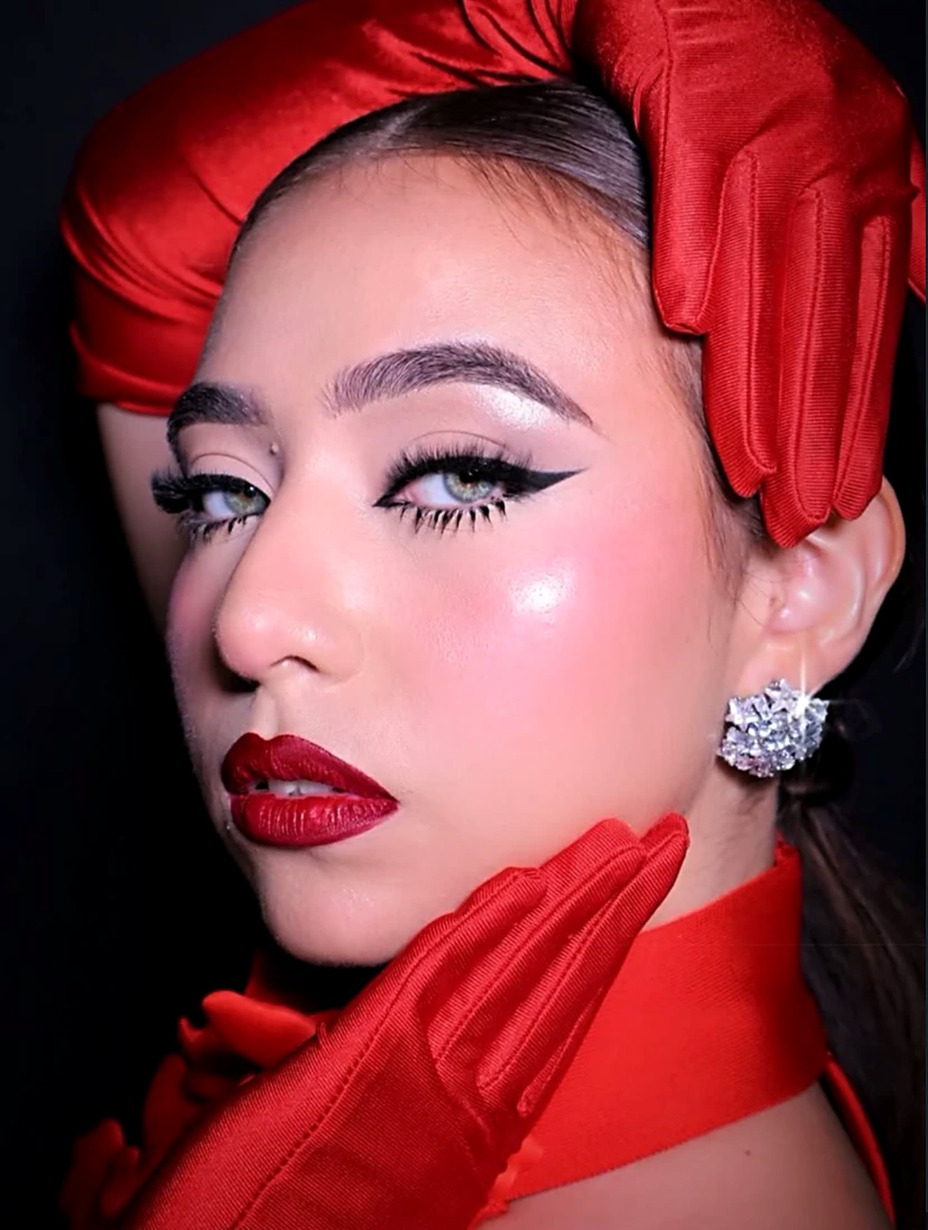 Maquillaje con delineado negro y labios rojos, con guantes rojos de satén
